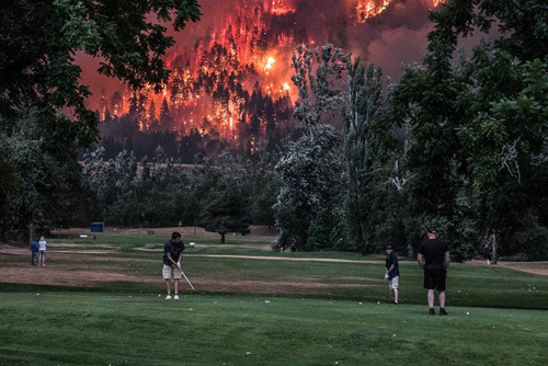 Golfers with forest fire burning behind them