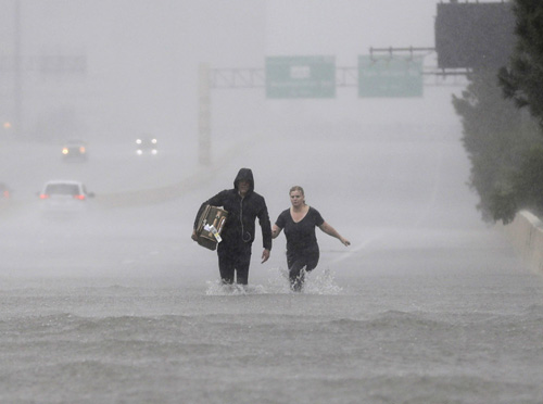 two people wading through a flooded freeway